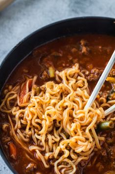 a close up of a bowl of noodles with chopsticks