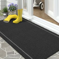 a pair of yellow rubber boots sitting on top of a door mat next to a potted plant