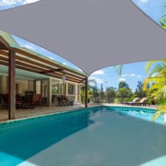 an outdoor swimming pool with shade covering it and chairs around the pool area, surrounded by palm trees