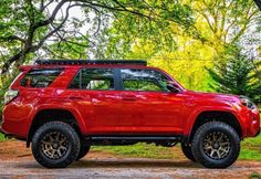 a red toyota 4runner is parked in the woods