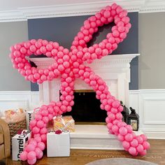 a pink balloon shaped like an x in front of a fireplace