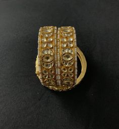 a gold and diamond ring with two rows of stones on the front, sitting on a black surface