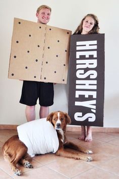 two people and a dog are holding cardboard signs