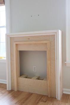 an empty room with a wooden fireplace in it