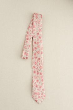 a pink flowered tie laying on top of a white table