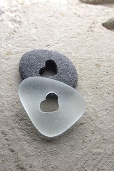 two pieces of sea glass sitting on the sand