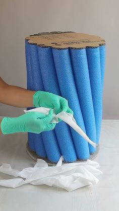 a person in green gloves is holding scissors near a blue tube with white paper on it