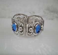 "Up for sale is this beautiful carved blue sapphire glass 925 sterling silver panel bracelet made in Mexico. It features 4 carved glass mask heads and four 1.5\" wide by 1.25\" high sterling silver hinged panels. The length is 7\" long, but fit 6.5\". the bracelet weighs 34.99 grams. On the box clasp it is marked \"Hecho En Mexico DF\" in a circle and in the middle it have \"0925 TNC\". This is in beautiful condition and would make a great gift. Please review all images carefully as they are als Unique Engraved Blue Bracelets, Blue Vintage Sterling Silver Bracelet, Vintage Carved Blue Jewelry, Vintage Blue Carved Jewelry, Blue Sterling Silver Engraved Bracelet, Elegant Blue Sterling Silver Bracelet Stamped 925, Blue Engraved Sterling Silver Bracelets, Elegant Blue Sterling Silver Bracelet, Glass Mask