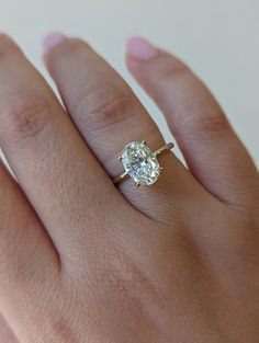 a woman's hand with a diamond ring on top of her finger, showing the center stone