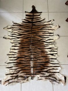 a brown and black animal skin rug on a tile floor with white tiles in the background