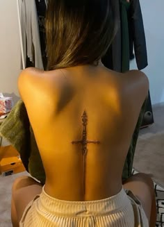 the back of a woman's body with a cross tattoo on her lower back