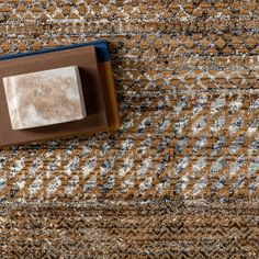 a brown and white rug with a square object on it's side in the middle