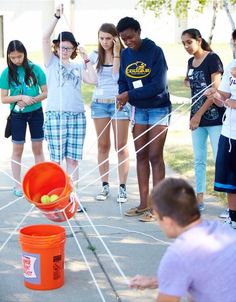 a group of people standing around an orange bucket