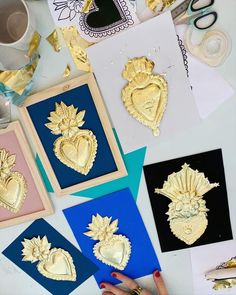 some gold and blue cards are laying out on a table with scissors, glue, paper, and other crafting supplies