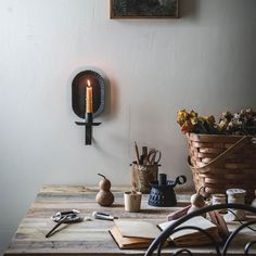 a wooden table topped with lots of clutter next to a wall mounted candle holder