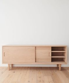 a wooden cabinet sitting on top of a hard wood floor next to a white wall