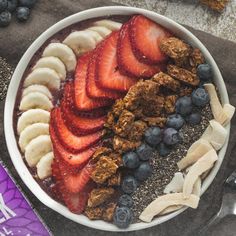 a bowl filled with granola, bananas and blueberries on top of a table