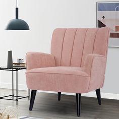 a pink chair sitting on top of a hard wood floor next to a black table