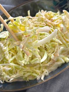 a bowl filled with coleslaw and chopsticks on top of a table