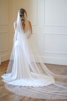 the back of a bride's veil as she stands in an empty room