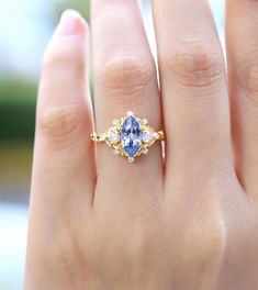 a woman's hand with a blue and white diamond ring on top of it