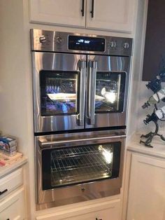 two ovens are built into the wall in this kitchen with white cabinets and stainless steel appliances