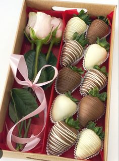 several chocolate covered strawberries in a box with pink ribbon and rose buds on the side