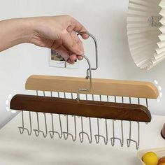 a person's hand holding a wooden hanger over a table