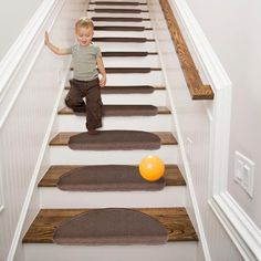 a young boy is climbing the stairs with an orange ball in front of him,