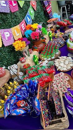 a table filled with lots of candy and snacks on top of purple cloth covered tables