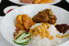 a white bowl filled with rice, meat and veggies on top of a table