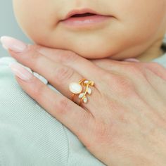 a close up of a person's hand with a ring on their finger and a baby in the background