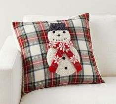 a pillow with a snowman on it is sitting on a white couch in front of a window