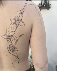 the back of a woman's upper body with flowers on her left arm and shoulder