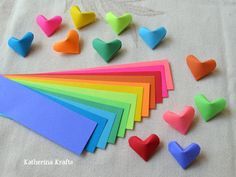 there are many different colors of hearts on the table and one is made out of paper