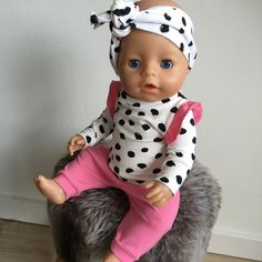 a baby doll is sitting on top of a stuffed animal that's wearing a polka dot shirt and pink pants