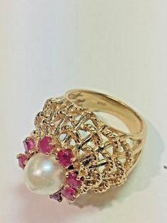 Vintage 14k Yellow Gold Dome White Pearl Red Ruby Domed Basket Weave Ring Size 5 Metal: 14k yellow gold, stamped Stones: (8) Natural Rubies measuring 2.5mm each, (1) Natural White Pearl Measuring 7.5mm with slight wear on top of the pearl Ring Size: 5 (can be resized upon request) Size: Sits 17mm high off the finger, Center cluster measures 15mm in diameter, 20mm wide (north to south) Hallmarked: 14k Textured rope design details on the basket This is an estate piece in very good condition. Pleas Fine Jewelry Yellow Gold Ruby Ring With Intricate Design, Exquisite Multi-stone Yellow Gold Ruby Ring, 14k Yellow Gold Ruby Ring With Intricate Design, Exquisite 14k Gold Ruby Ring, Gold Ruby Rings With Intricate Design, Gold Ruby Ring Stamped 14k, White Ruby Ring In 14k Gold, Gold Ruby Ring With Intricate Design, Fine Jewelry Gold Ruby Ring With Intricate Design