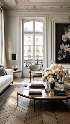 a living room filled with furniture and flowers on top of a coffee table in front of a window