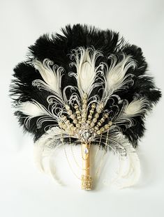 a black and white feathered fan with pearls on it's head is displayed against a white background