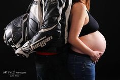 a pregnant woman and man are standing next to each other with their back packs on