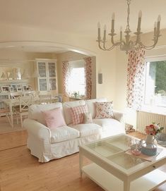 a living room filled with furniture and a chandelier hanging from the ceiling over a wooden floor