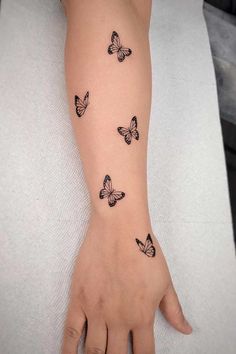 a woman's arm with black butterflies on the left side of her hand and one is