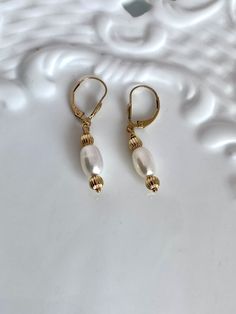 two pearls are hanging from gold - plated earrings