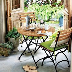 an outdoor table with two chairs and a potted plant on the outside patio area