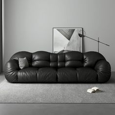 a black leather couch sitting in a living room next to a painting on the wall