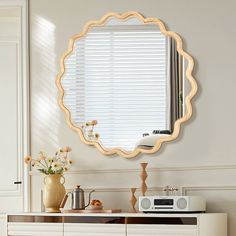 a mirror that is sitting on top of a dresser next to a microwave and vase