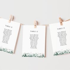 three place cards hanging from clothes pins with mountains in the background and text on them