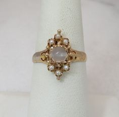 a close up of a ring on a white napkin with pearls and gold trimmings