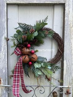 a wreath with pine cones, berries and greenery hangs on an old wooden door