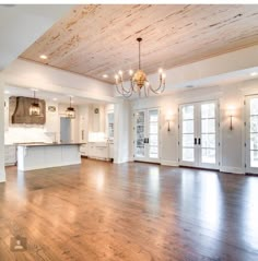 an empty living room with wood floors and chandelier